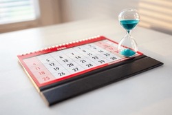 Hour Glass On Top Of Calendar Concept For Time Slipping Away For Important Appointment Date, Schedule And Deadline