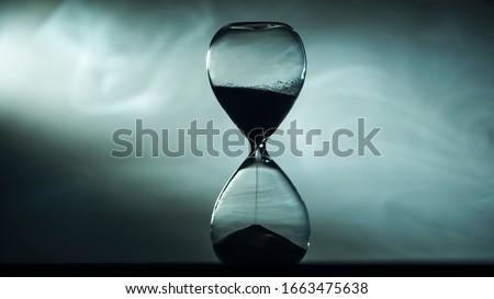 Hourglass against the fog illuminated by the spotlight