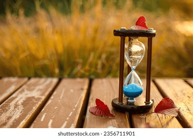 Hourglass with autumn leaves on bench in park, closeup - Shutterstock ID 2356711901