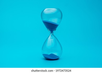 Hourglass With Blue Sand On Blue Background.