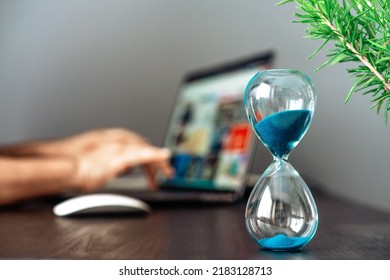 Hourglass With Blue Sand On The Desk