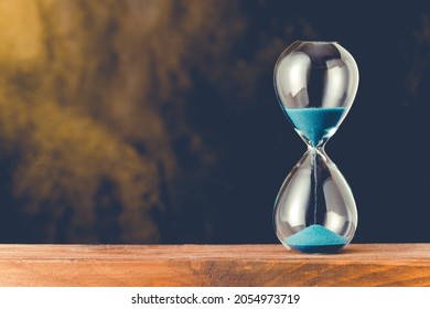 Hourglass with blue sand on the wood
