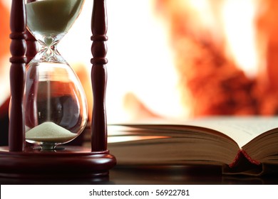 hourglass and book on background of fireplace
