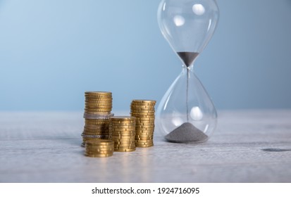 Hourglass with coins on the gray background.
 - Powered by Shutterstock