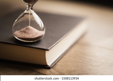 Hourglass Countdown On A Book. Hourglass And A Bible Symbolizing The End Times. Time Is Running Out.