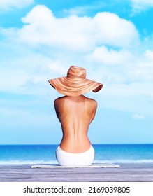 Hourglass Figure. Rear View Of Sexy Topless Woman Sitting On A Porch Facing The Sea.