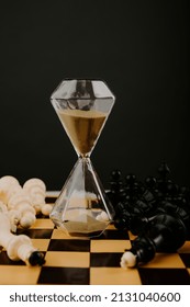 Hourglass With Gold Sand And Chessboard On A Dark Background. Strategy, Management Or Leadership Concept. Vertical Image