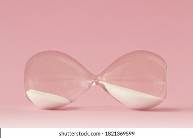 Hourglass lying on pink background - Concept of time and woman - Shutterstock ID 1821369599