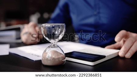 Hourglass On Desk. Running Late With Invoice Or Bill