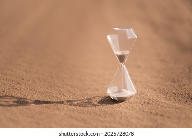 An hourglass on hot sand in desert in hot summer sun