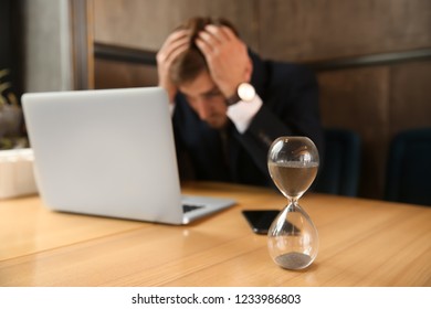 Hourglass on table of troubled businessman sitting in cafe - Shutterstock ID 1233986803