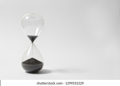 Hourglass On White Background, Running Out Of Time, Black Sand Flowing From Upper Bulb To Lower Bulb Till Deadline