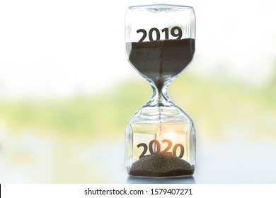 The Hourglass Placed On The Table Tells The Time The Year 2019 Is About To End. The Year 2020 Is About To Start. Happy New Year. With Copy Space.