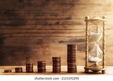 Hourglass with pouring sand and stacks of shiny small value copper euro coins depicting a bar graph. Concept of time value of money. - Powered by Shutterstock