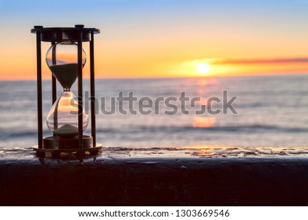 Hourglass or sand timer in front of a beatiful clear sunrise or sunset.