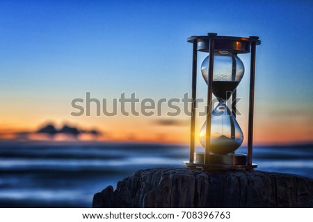 Hourglass or sand timer in front of a beautiful clear sunrise or sunset.