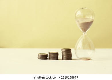 Hourglass And Stack Of Coins On Table, 