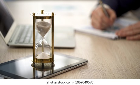 Hourglass standing on table with sand trickling, man working with graphs, data, stock footage - Powered by Shutterstock - Get 15% off with code: PIKWIZARD15