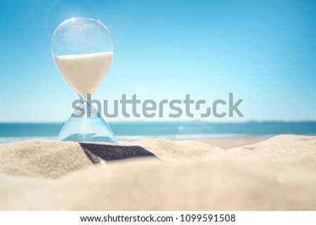 Hourglass time on a beach in the sand with blue sky and copy space