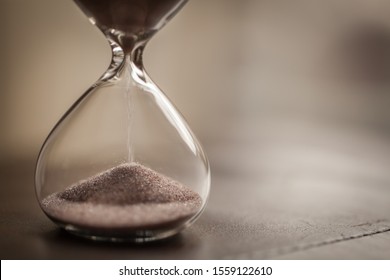 Hourglass As Time Passing Concept For Business Deadline, Urgency And Running Out Of Time. With Blurred Background And Copy Space. Sandglass.