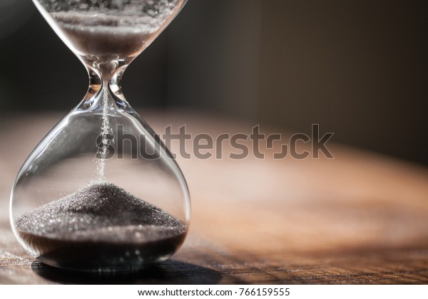 Hourglass as time passing concept for business
deadline, urgency and running out of time. Sandglass, egg timer on
wooden floor showing the last second or last minute or time out. 
With copy space.