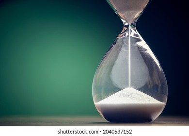 Hourglass time passing green background concept for business deadline, urgency and running out of time