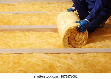 House attic insulation - construction worker installing glass wool 