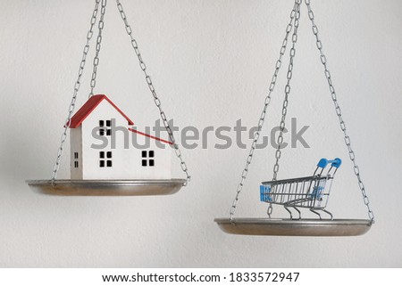 House balance equilibrium concept. House and shopping trolley on the scales.