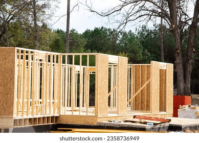 House with basement and slab foundation, retaining concrete wall under construction, timber frame post, beam and OSB (Oriented Strand Board) plywood sheathing Atlanta, Georgia. Suburban American home - Shutterstock ID 2358736949