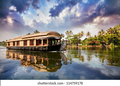 House boat in backwaters near palms at cloudy blue sky in Alappuzha, Kerala, India
