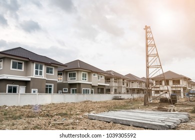 house building at construction site with pile driver and precast concrete piles