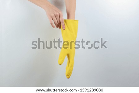 House cleaning concept. Female hands wear yellow rubber gloves for cleaning on a gray background