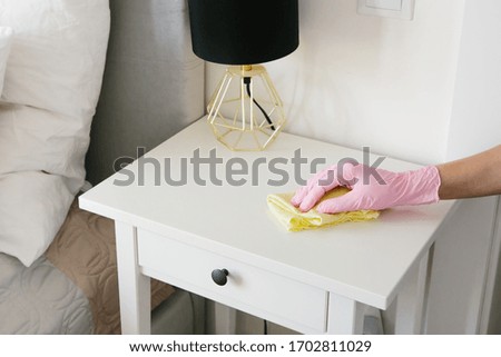 House cleaning and disinfection: a woman in gloves cleans white furniture from dust.