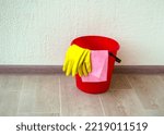 House cleaning. The photo shows a red bucket, rubber gloves and a rag.