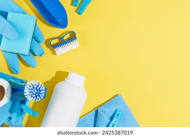 House cleaning product equipment displayed on yellow background. Top view of detergent bottle, blue rubber gloves, sponge, brushes and clothespins. Space for design - Powered by Shutterstock