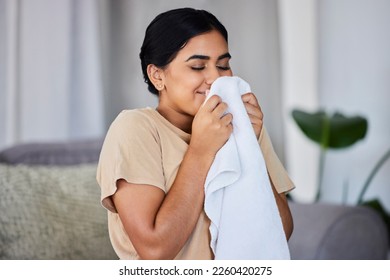 House, cleaning and woman smelling laundry on a sofa, happy and relax alone in her home. Fresh, linen and smiling domestic worker excited for freshness, results and soft fabric in household chores