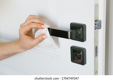 House Cleaning: A Woman Wipes A Doorknob From Dust And Bacteria. Prevention Of Influenza And Covid-19 Infection.