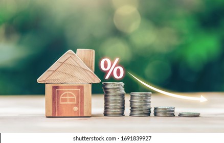 House and coins place on the wood table is ladder with white illustration shows decreasing of interest rates. planning savings money of coins to buy a home concept for property ladder, mortgage.