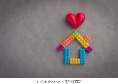 House concept with plastic blocks toy and heart object on leather floor