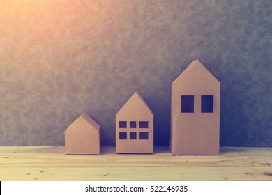 house concept with house shape cardboard on wooden floor and grey wall with free copyspace for your creativity ideas text