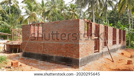 House construction in Kerala, India. Brick walls, and door and window frames of a partially built house in a rural background. Sustainable housing.                                 