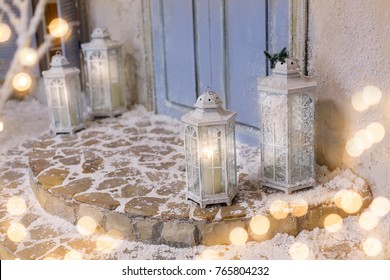 House Decorated For Christmas. Luminous Lanterns On Snowy Stairs At Porch. Beautiful Winter Christmas Background.