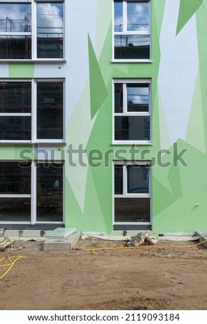 house detail at construction site with modern apartment block, artistically designed with pattern of polygonal shapes symbolizing abstracted floral elements, streetart, copy space