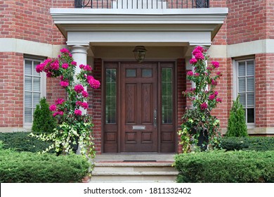 House with elegant entrance with portico, flowers, and wooden door with sidelights