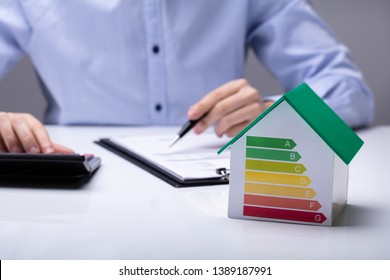 House With Energy Efficiency Rate In Front Of Businesspeople Working In Office While Using Calculator - Powered by Shutterstock