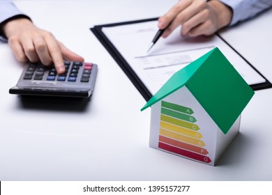 House With Energy Efficiency Rate In Front Of Businesspeople Working In Office While Using Calculator - Powered by Shutterstock