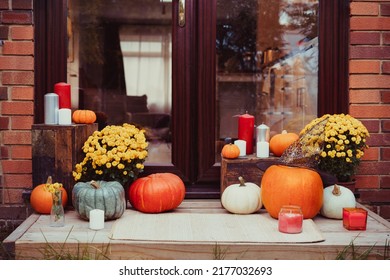 House entrance decorated for traditional autumn holidays. Porch of the house decorated with pumpkins, flowers, and candles for Thanksgiving or Halloween. Selective focus.