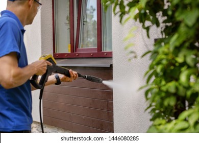 House Facade Cleaning Service. Man Washing Wall With High Pressure Washer