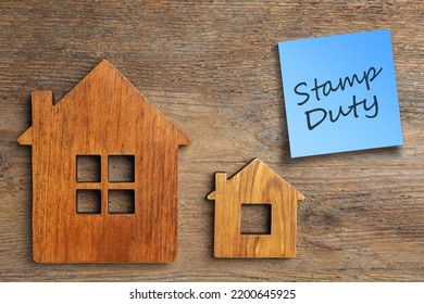 House figures and sticky note with text Stamp Duty on wooden background, flat lay