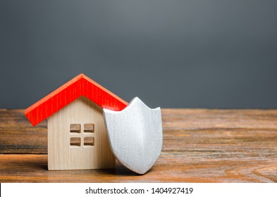 House figurine and protective shield. The concept of home security and safety. Alarm systems. The inviolability of private property, protection against raiders or unauthorized access.